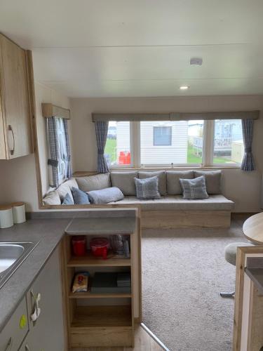 a living room with a couch in front of a window at Whitstable, DP42, 2 bed park home, Alberta Holiday Park in Whitstable