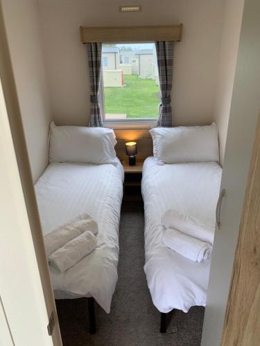 two beds in a small room with a window at Whitstable, DP42, 2 bed park home, Alberta Holiday Park in Whitstable