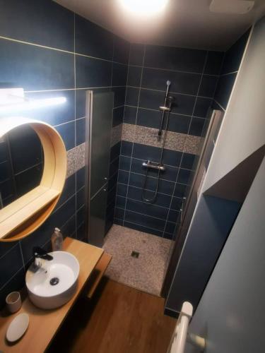 une salle de bain carrelée bleue avec un lavabo et une douche dans l'établissement Au numéro 3 (Le Min'ion), à Châteauroux