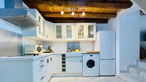 - une cuisine avec des placards blancs et un lave-linge/sèche-linge dans l'établissement La Cantarera, à Linares de la Sierra
