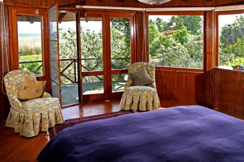 1 Schlafzimmer mit einem Bett, 2 Stühlen und Fenstern in der Unterkunft Perfect Home with Private Beach by Iznik Lake in Bursa