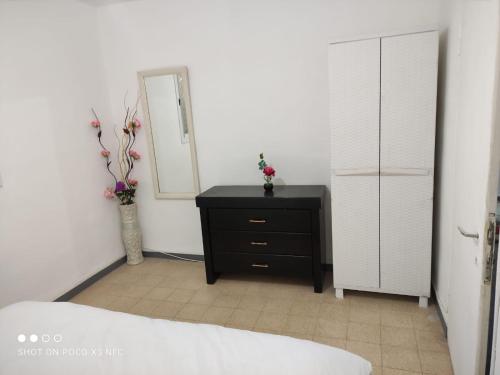 a bedroom with a black dresser and a mirror at vacation house דירת אירוח פרטית 3 חדרים עפולה in El ‘Affūle