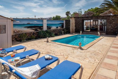a swimming pool with blue lounge chairs and a house at Villa Maravilla piscina climatizada in Villaverde