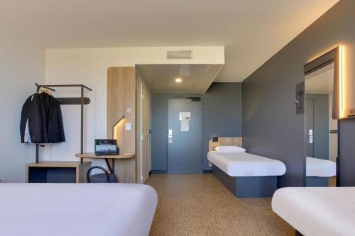 ein Krankenhauszimmer mit 2 Betten und einem Spiegel in der Unterkunft B&B HOTEL Reims Croix Blandin in Reims