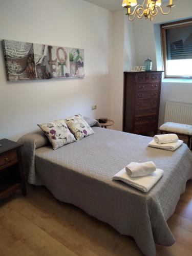 a bedroom with a bed with two towels on it at ATICO CALDAS in Caldas de Reis