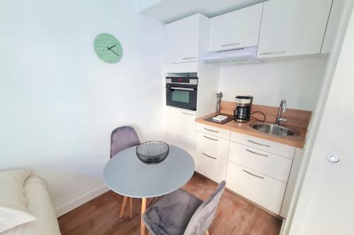 a small kitchen with a white table and chairs at Le Poulorio 3 - Studio - Proche Gare By Locly in Lorient