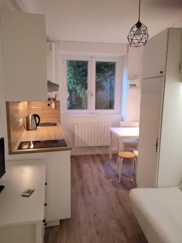 a kitchen with white cabinets and a table with a sink at Studio Croix Rousse in Lyon