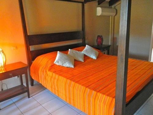 een slaapkamer met een oranje bed met 2 kussens bij duplex, 2 bedrooms, 2 couples sea view overlooking the village of DESHAIES in Deshaies