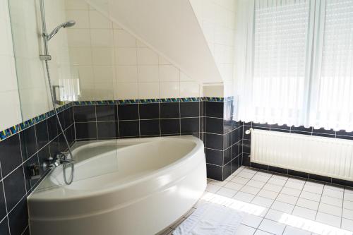 Hotel-Restaurant Moris في Walferdange: حوض استحمام أبيض في حمام مع نافذة