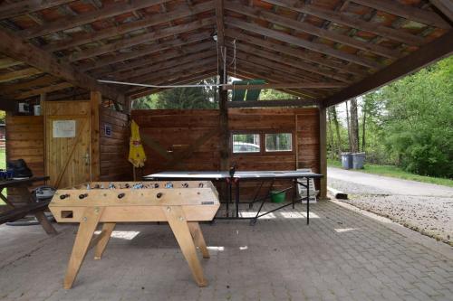 stół do ping ponga przed drewnianą kabiną w obiekcie Vacance conviviales dans les Vosges 8 Gîtes w mieście Ban-de-Sapt