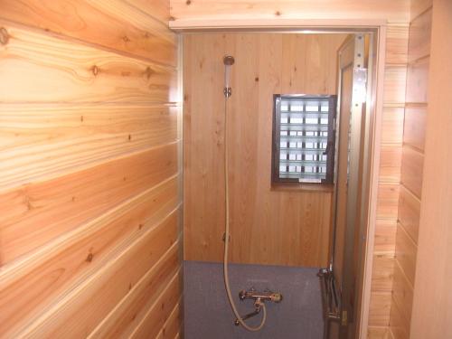 a bathroom with wooden walls and a shower stall at Shukubo Komadori-Sanso in Ome