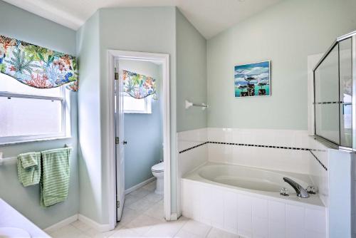 a white bathroom with a tub and a toilet at Merritt Island Home with Grill and Saltwater Pool in Merritt Island