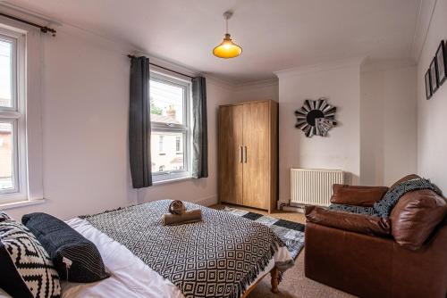 a bedroom with a bed and a chair and a clock at City Centre 3 Bed - Long Stay Offer - Free Parking in Canterbury