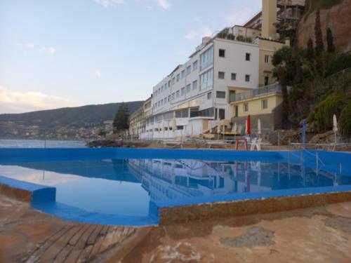 - une piscine d'eau bleue en face d'un bâtiment dans l'établissement Hotel La Perla Del Capo, à Ospedaletti