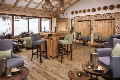a bar in a room with chairs and tables at Berghotel Rehlegg in Ramsau