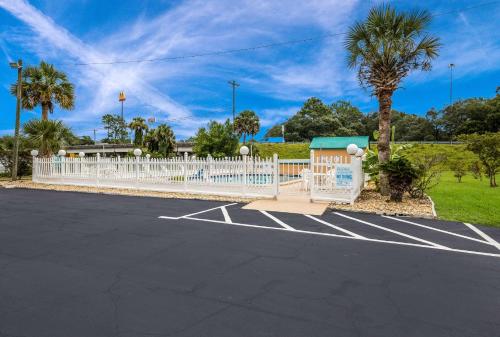 a parking lot with a white fence and palm trees at Quality Inn White Springs Suwanee in Live Oak