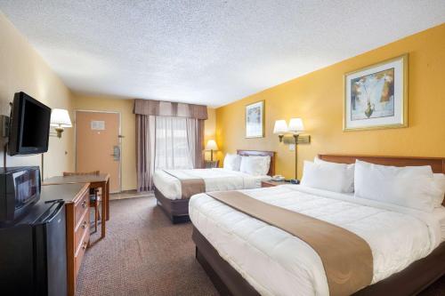 a hotel room with two beds and a flat screen tv at Quality Inn White Springs Suwanee in Live Oak