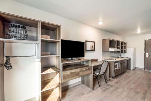 a kitchen with a desk with a television and a refrigerator at WoodSpring Suites Tucson-South in Tucson