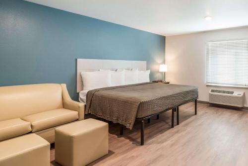 a bedroom with a bed and a couch and a chair at WoodSpring Suites Tucson-South in Tucson