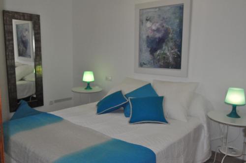 a bedroom with a bed with blue pillows and two lamps at Casa Amanada in Santa Margalida