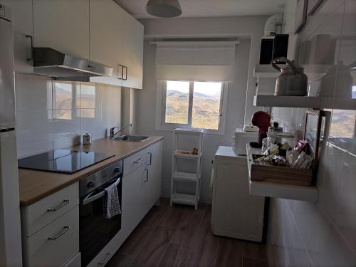 a kitchen with white cabinets and a sink and a window at La casa de mi Rosa in Olvera