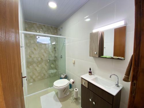 a bathroom with a toilet and a shower and a sink at Calefe Suítes in Penha