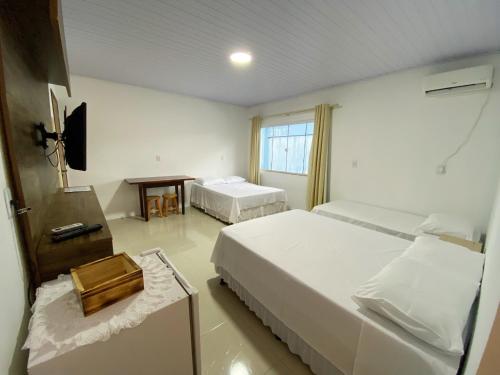 a hotel room with two beds and a television at Calefe Suítes in Penha