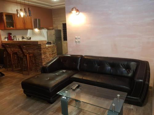 a living room with a black leather couch and a table at Superbe appartement en résidence in Cotonou