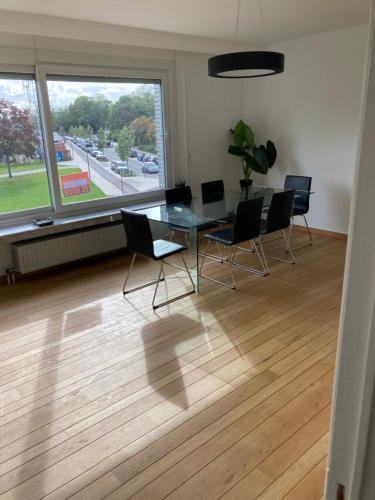a dining room with a table and chairs and a large window at Lichtrijk mooi appartement met zicht op hof van Roosendael in Antwerp