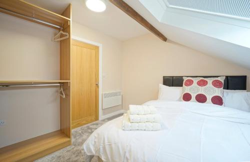 ein Schlafzimmer mit einem großen weißen Bett mit roten und weißen Kissen in der Unterkunft Alpha Lofts, Huddersfield in Huddersfield