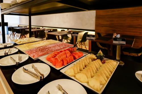 a table with several trays of different types of food at Transamerica Fit Vitória Praia de Camburi in Vitória