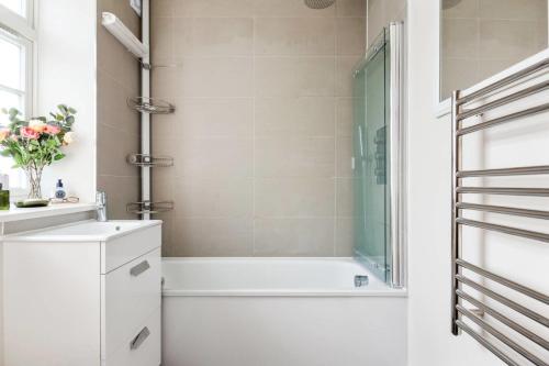 Large Luxury Studio in Heart of Richmond في ريتشموند: حمام مع دش وحوض استحمام ومغسلة