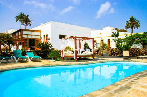 
a beach with a pool, chairs, and a pool table at Casa Rural Villa Lola Y Juan in Haría
