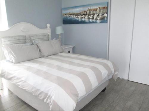 a white bed in a bedroom with a painting on the wall at Seabreeze At 301 in Ballito