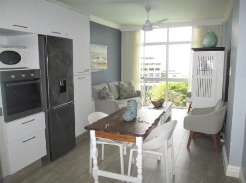 a living room with a table and a kitchen at Seabreeze At 301 in Ballito