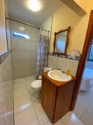 a bathroom with a sink and a toilet and a mirror at La Peregrina Galapagos B&B in Puerto Ayora