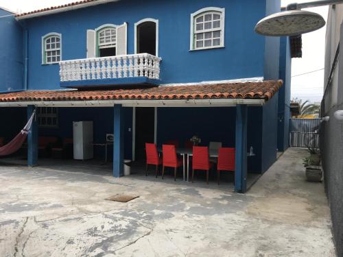 a blue house with red chairs and a balcony at Lurviz Home Suítes in Cabo Frio
