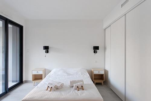 une chambre blanche avec un lit et deux tables de nuit dans l'établissement Appartement Maréchal - Welkeys, à Cannes