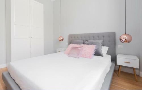 - une chambre blanche avec un grand lit blanc et des oreillers roses dans l'établissement Farini Suite, à Milan