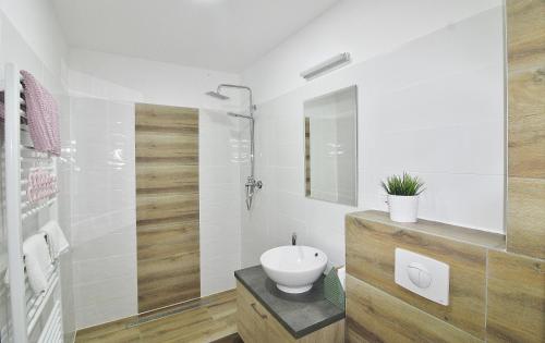 biała łazienka z umywalką i toaletą w obiekcie Apartmany Troll w mieście Bublava