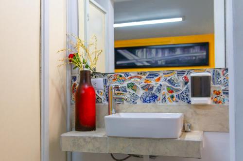 a bathroom with a sink and a red vase on a counter at Hostal Talavera in Puebla