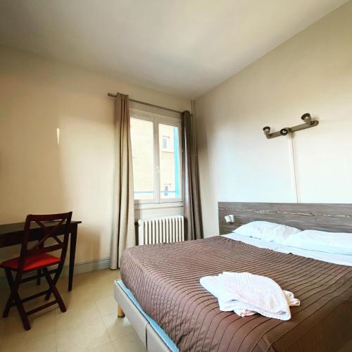 a bedroom with a bed and a chair and a window at Hotel Le Midi Clermont-Cournon in Cournon-dʼAuvergne