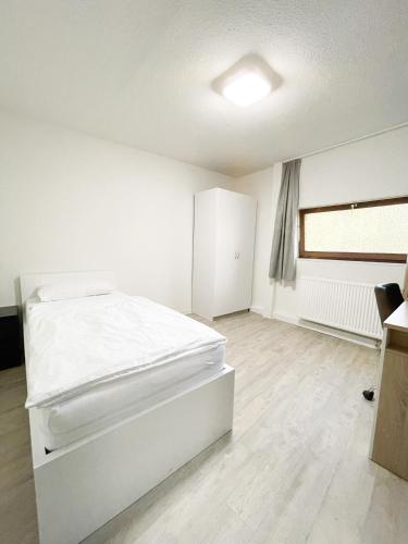 a white bedroom with a bed and a window at Traumhaftes Privatzimmer in Karlsruhe in Karlsruhe