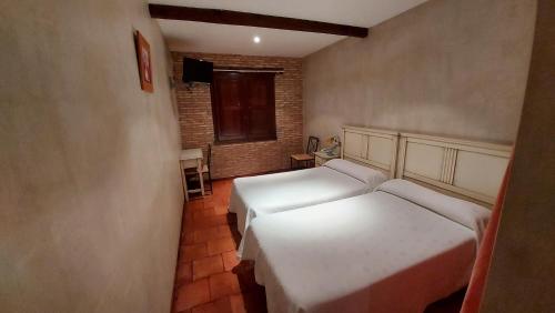 a small room with two beds and a window at Hotel Rural Carlos I in Garganta la Olla