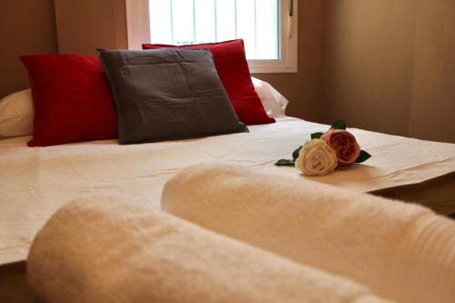 a white bed with red pillows and two roses on it at WISH SUITE MORERA in Seville