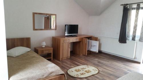 1 dormitorio con 1 cama y escritorio con TV en Zodiac en Caransebeş
