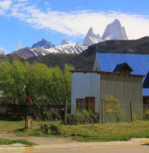 a barn with a blue roof with mountains in the background at Don Galle in El Chalten