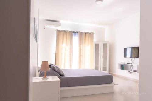 a white bedroom with a bed and a window at Urban Aparthotel in Praia