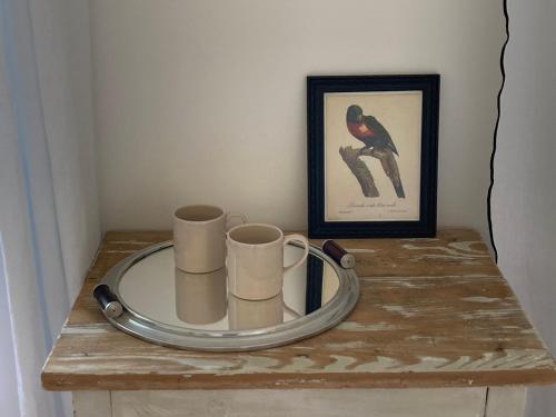 a wooden table with two mugs and a picture at Chambres d'hôtes - La Maison 19 in Niort