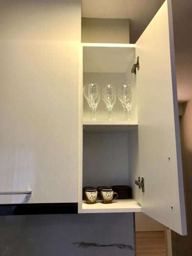 a white cabinet with wine glasses in it at Home away from Home Apartment in Durrës